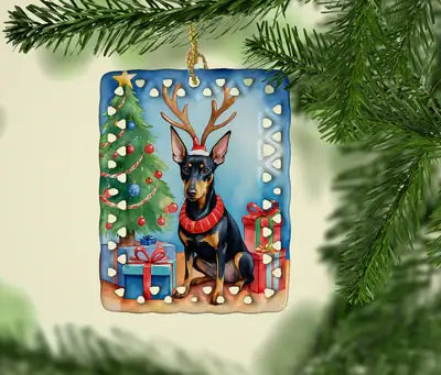 Christmas ornament featuring a Doberman with antlers, surrounded by a tree and gifts.